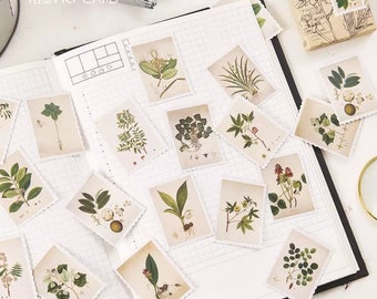May include: A sheet of decorative stickers featuring various botanical illustrations. The stickers are printed on white paper with a scalloped edge and feature a variety of green plants and flowers.