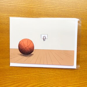 May include: A basketball on a brown wood floor with a basketball hoop in the background. The basketball is orange and brown and has black lines. The hoop is white and has a black net.