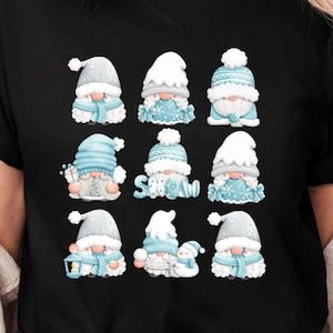 May include: A black t-shirt featuring a graphic print of nine winter gnomes arranged in a grid. The gnomes wear light blue and white hats, scarves, and winter clothing, with some holding lanterns or snowmen. The word SNOW is written in blue.