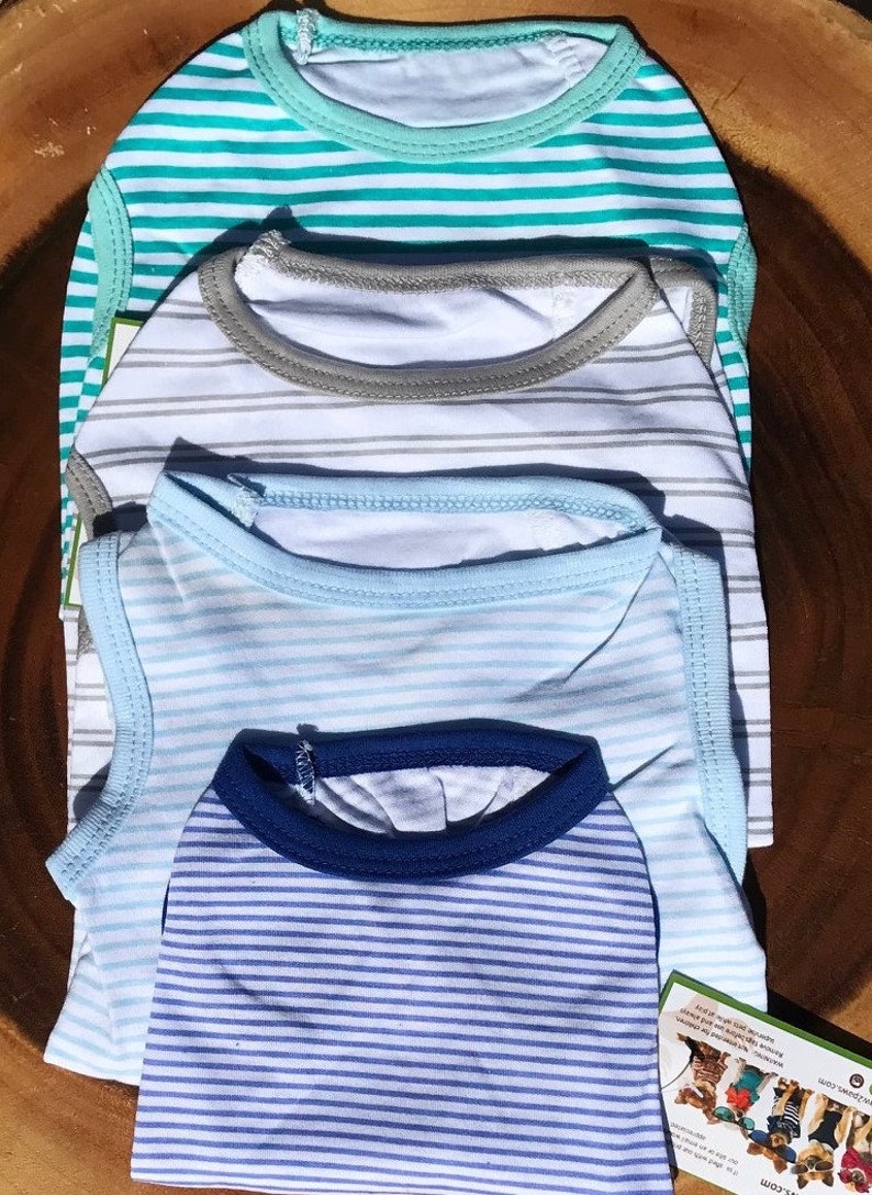 May include: Four striped tank tops for dogs in blue, white and grey colours. The tank tops are stacked on top of each other. The top tank top is turquoise and white striped. The second tank top is grey and white striped. The third tank top is light blue and white striped. The bottom tank top is dark blue and white striped.