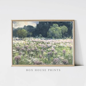 Puede incluir: Una pintura al agua enmarcada que representa un campo de flores silvestres moradas con un bosque en el fondo. La pintura tiene una sensación ligera y aireada y es perfecta para agregar un toque de naturaleza a cualquier habitación.