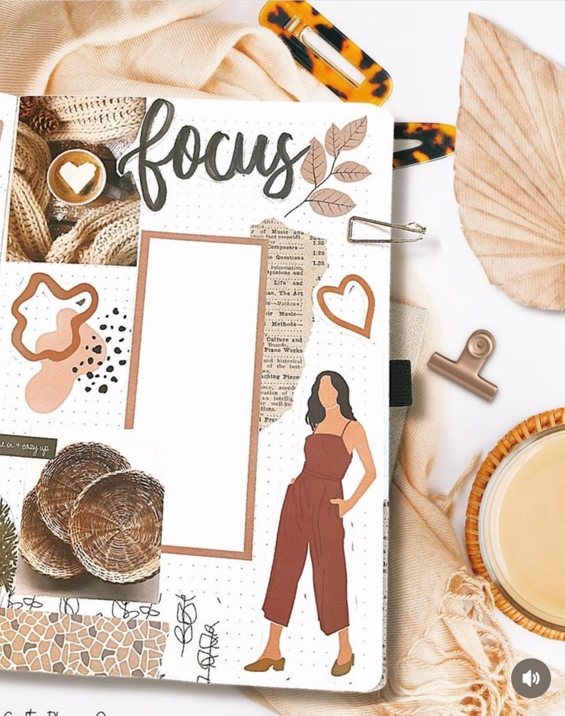 May include: A white planner page with brown and beige patterned paper, stickers, and drawings. The page has the word "focus" written in black cursive. There is a drawing of a person wearing a brown jumpsuit. The page is decorated with a brown leaf, a heart, and a brown and white patterned circle.