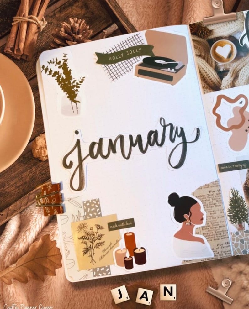 May include: A white planner page with the word "January" written in black cursive script. The page is decorated with stickers, including a record player, candles, and a woman with a bun. The page also includes the text "Holly Jolly" and "made with love".