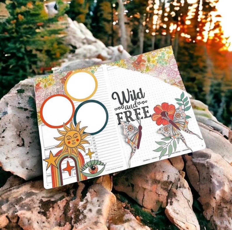 May include: A planner with a floral design on the cover. The planner has a page with a sun, rainbow, and eye design. The other page has the text "Wild and FREE" with butterflies and flowers.