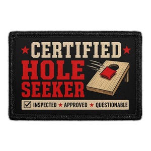 May include: A rectangular black patch featuring the text CERTIFIED HOLE SEEKER in beige and red. An illustration shows a wooden cornhole board with a red bean bag landing on it. Below, a box contains the text INSPECTED, APPROVED, and QUESTIONABLE.