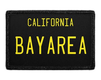 Könnte beinhalten: Ein rechteckiger schwarzer Aufnäher mit gesticktem Rand, der den gelben Text CALIFORNIA in der oberen Zeile und BAYAREA in der unteren Zeile in einer fetten serifenlosen Schrift zeigt. Das Design ähnelt einem Nummernschild auf Stoff.