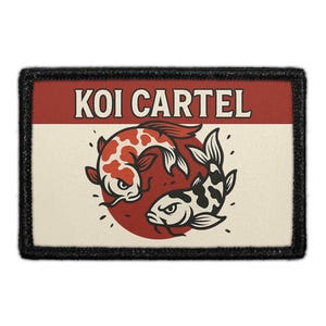 May include: A rectangular embroidered patch with a black border featuring the text KOI CARTEL in white on a red background. Below, two stylized koi fish, one red and white and one black and white, are arranged in a circle on a cream background.