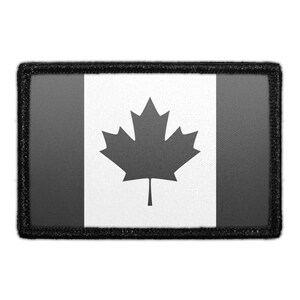 May include: A rectangular patch featuring a monochromatic design of the Canadian flag. The center panel is white with a dark gray maple leaf, flanked by two dark gray vertical side panels. The entire patch is bordered by a thick black stitched edge.