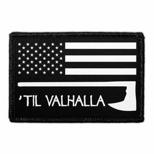 May include: A rectangular black patch featuring a white graphic of the American flag with a stylized axe head integrated into the design. Below the flag, the text 'TIL VALHALLA is printed in a bold, white, sans-serif font on the black background.