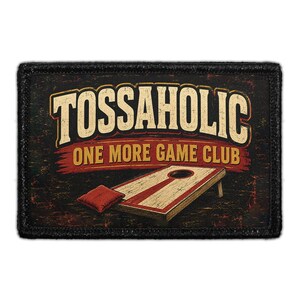 May include: A rectangular patch with a black border featuring the text "TOSSAHOLIC" in large cream letters above "ONE MORE GAME CLUB" in yellow. Below the text is an illustration of a wooden cornhole board and a single red bean bag.