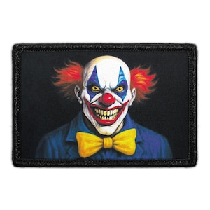 May include: A rectangular embroidered patch featuring a clown with white face paint, blue eye makeup, a red nose, and a wide grin with sharp teeth. The clown has bright red hair, wears a blue jacket, and a large yellow bow tie on a black background.