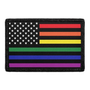 May include: A rectangular patch featuring a modified American flag design. The canton is black with white stars, while the stripes consist of alternating horizontal bands of red, orange, yellow, green, blue, and purple, separated by thin black lines.
