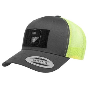 May include: A gray snapback baseball cap with a neon yellow mesh back. The cap features a black rectangular patch with a design and the text "THE CLASSICS SNAPBACK YUPOONG SINCE 1974" on the brim.
