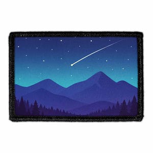May include: A rectangular embroidered patch featuring a night landscape with a dark blue forest in the foreground, layered purple mountain silhouettes in the midground, and a gradient blue sky filled with small white stars and a bright shooting star.