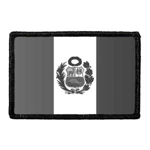 May include: A rectangular patch featuring a grayscale version of the Peruvian flag. The design consists of three vertical bands with the national coat of arms centered in the middle white band, all enclosed by a thick, textured black border.