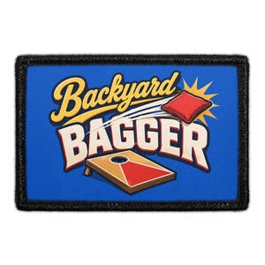 May include: A rectangular patch with a black border featuring a blue background and the text Backyard BAGGER in yellow and white. The design includes a graphic of a red bean bag flying toward a wooden cornhole board with a red triangular target.