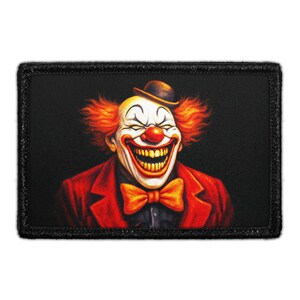 May include: A rectangular patch featuring a smiling clown with orange hair, a red nose, and a red suit. The clown wears a small bowler hat and a yellow bow tie. The background is black.