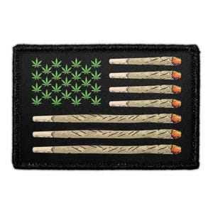 May include: A rectangular black patch featuring a graphic design of the American flag. The canton consists of green cannabis leaf icons, while the stripes are represented by six horizontal hand-rolled cigarettes with glowing orange embers.