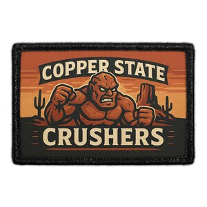 May include: A rectangular patch with a black border features a muscular, brown figure with an angry expression. The text "COPPER STATE CRUSHERS" is arched above the figure. The background depicts a desert scene with cacti and a sunset.