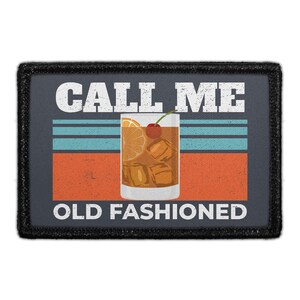 May include: A rectangular patch with a black border featuring the text CALL ME OLD FASHIONED in white. The center shows a glass of amber liquid with ice cubes, an orange slice, and a red cherry against a background of horizontal teal and orange stripes.