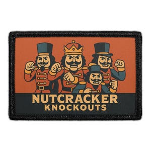 May include: A rectangular patch with a black border features a cartoon illustration of four nutcracker figures in various poses. The figures are in red, black, and gold uniforms. The text "NUTCRACKER KNOCKOUTS" is displayed in a bold font.
