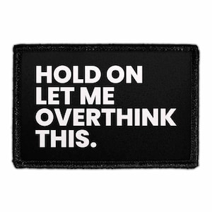 May include: A rectangular black patch with a stitched border featuring the white text "HOLD ON LET ME OVERTHINK THIS." The lettering is arranged in four lines, utilizing a bold, sans-serif font that stands out against the dark fabric background.