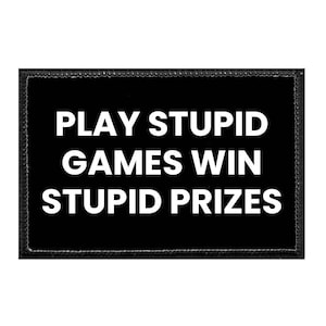 May include: A rectangular black patch with a stitched border featuring the white text PLAY STUPID GAMES WIN STUPID PRIZES in a bold, sans-serif font. The patch has a clean, uniform design with high contrast between the black background and white letters.