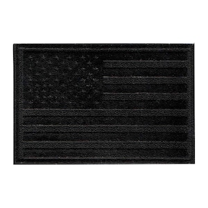 May include: A rectangular, black patch featuring the embossed design of the American flag. The flag's stars and stripes are clearly defined, creating a textured appearance. The patch is likely made of a durable material.