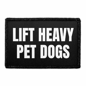 May include: A rectangular black patch with a stitched border featuring the white text LIFT HEAVY PET DOGS in a bold, sans-serif font. The patch has a clean, uniform design with high contrast between the white lettering and the black fabric background.