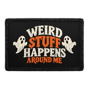 May include: A rectangular black patch featuring the white and orange text "WEIRD STUFF HAPPENS AROUND ME" in a distressed font. Two white ghost illustrations with hollow eyes and mouths are positioned on the left and right sides of the text.