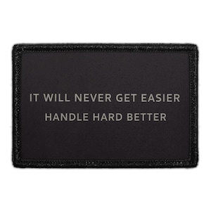 May include: Black rectangular patch with the text "IT WILL NEVER GET EASIER HANDLE HARD BETTER" in silver lettering. The patch has a black border with a textured appearance. The patch is likely designed to be sewn or attached to clothing or gear.