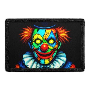 May include: A rectangular patch featuring a colorful clown face with a sinister expression. The clown has a red nose, yellow eyes, and orange hair. The face is divided into sections of blue, green, yellow, and red, stitched together. The patch has a black border.