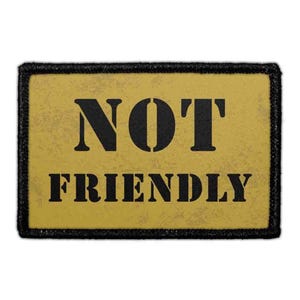 May include: A rectangular patch with the words "NOT FRIENDLY" in bold black letters on a yellow background. The patch has a black border and a distressed, textured appearance.