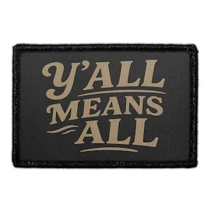 May include: A rectangular black patch with the phrase "Y'ALL MEANS ALL" in tan lettering. The patch has a black border and a textured appearance. The text is in a stylized, vintage font.