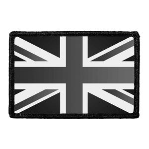May include: A rectangular patch featuring a monochromatic Union Jack flag design in shades of black, gray, and white. The patch has a thick, solid black stitched border framing the central flag pattern, which displays the iconic cross and diagonal lines.