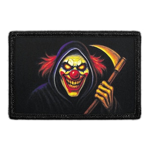 May include: A rectangular embroidered patch featuring a graphic illustration of a clown with a red nose, yellow eyes, and a wide grin. The clown wears a dark hooded cloak and holds a large golden scythe in one hand against a black background.