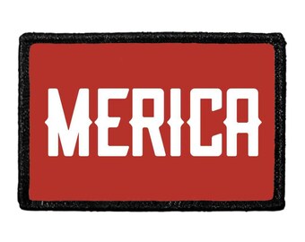 May include: A rectangular patch with a red background and a thick black border. The word MERICA is printed in large, bold, white capital letters across the center of the patch. The font features a distinct, angular, and blocky typeface style.