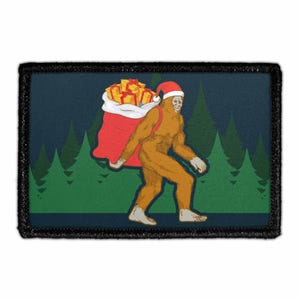 May include: A rectangular patch featuring a cartoon Bigfoot wearing a Santa hat and carrying a red sack filled with wrapped gifts. The background is a dark blue with green pine trees. The patch has a black border.