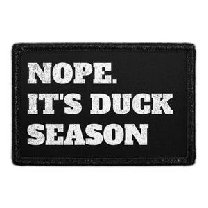 May include: A rectangular black patch with a stitched border featuring the white distressed text NOPE. IT'S DUCK SEASON. The lettering is arranged in three lines with a bold, sans-serif font style, creating a high-contrast graphic design.