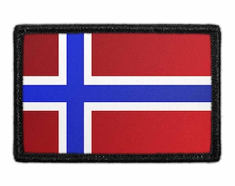 Może przedstawiać: Prostokątna haftowana naszywka przedstawiająca flagę Norwegii. Wzór składa się z czerwonego tła z niebieskim krzyżem skandynawskim z białą obwódką. Naszywka wykończona jest grubym, czarnym obszyciem wokół całego obwodu.