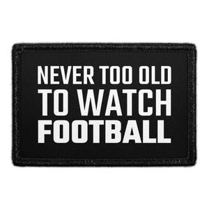 May include: A rectangular black patch with a stitched border featuring the white text NEVER TOO OLD TO WATCH FOOTBALL in a bold, sans-serif font. The design is centered on the black fabric background, creating a high-contrast, legible appearance.