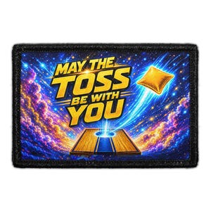 May include: A rectangular patch with a black border featuring a cosmic background of purple and blue nebulae and stars. The text MAY THE TOSS BE WITH YOU is in yellow, with a wooden cornhole board and a flying yellow bean bag in the center.