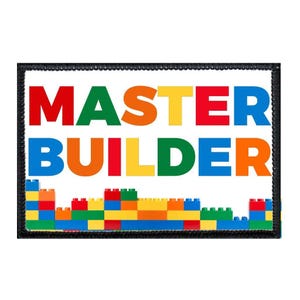 May include: A rectangular embroidered patch with a black border featuring the text MASTER BUILDER in bold, multi-colored block letters. Below the text is a graphic representation of a wall constructed from colorful plastic building bricks.