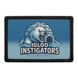 May include: A rectangular patch with a black border. The patch features a blue background with a white polar bear emerging from an igloo. The text "IGLOO INSTIGATORS" is below the bear.