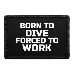 May include: A rectangular black patch with a stitched border featuring the white text BORN TO DIVE FORCED TO WORK in a bold, sans-serif font. The design is centered on the fabric surface, creating a clear contrast between the dark background and the lettering.