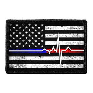 May include: A rectangular patch featuring a distressed American flag design in black and white. A horizontal line runs across the center, transitioning from blue on the left to red on the right, with a white heartbeat EKG line overlaying the center.