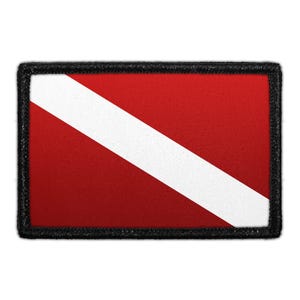 May include: A rectangular patch featuring the red and white diver down flag design. The patch has a bold red background bisected by a single diagonal white stripe running from the top left to the bottom right, all enclosed by a thick black border.