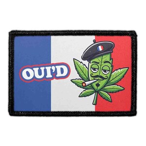 May include: A rectangular embroidered patch featuring the French flag in blue, white, and red. The text OUI'D is printed in white with a red outline. A green cannabis leaf character wears a black beret and has a mustache while smoking.