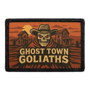 May include: A rectangular patch with a black border features a skull wearing a cowboy hat, set against an orange sunset with two rustic buildings. The text "GHOST TOWN GOLIATHS" is displayed in a bold, vintage font.