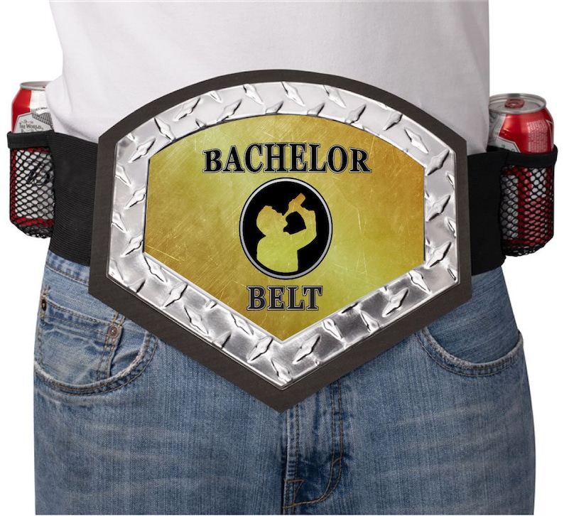 May include: A black and silver belt with a gold-colored center panel that says "Bachelor Belt" and features a silhouette of a person drinking. The belt has two mesh pockets on either side for holding drinks.